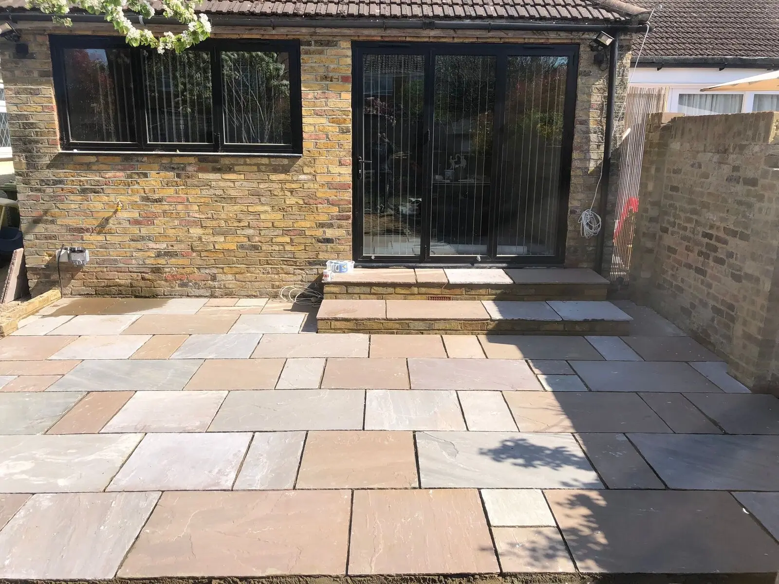 Indian sandstone patio laid in a mixed-size pattern outside a modern brick extension