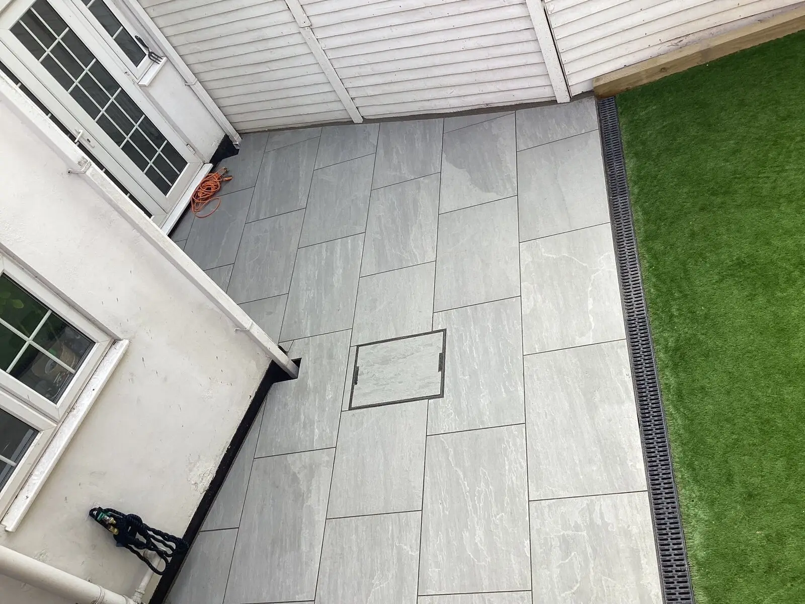 Grey porcelain paving laid flush against a freshly cut lawn